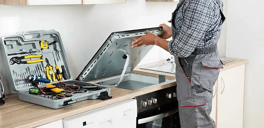 Handyman repairing a cooktop and checking wiring connections in Kansas City, KS