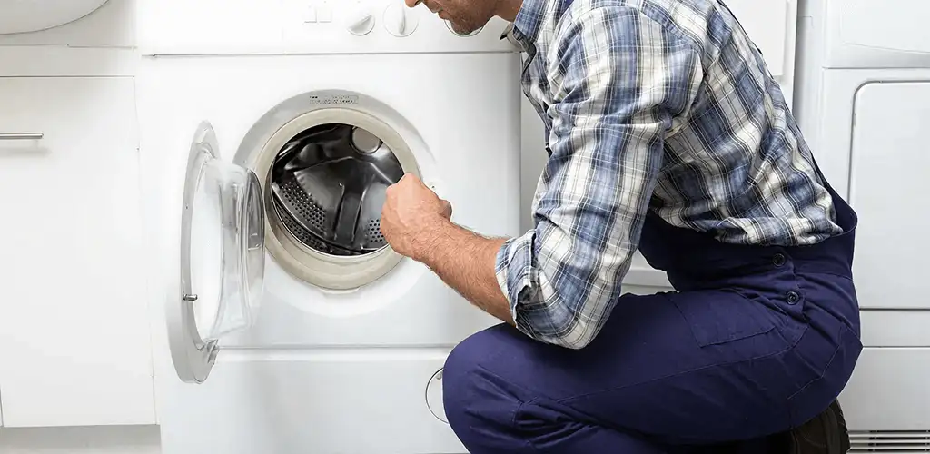 Handyman inspecting a dryer drum and internal parts for repair in Kansas City, KS