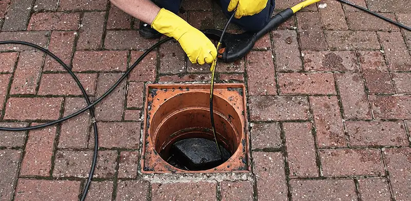 Drain cleaning technician using a drain snake to clear a clogged drain in Kansas City, KS