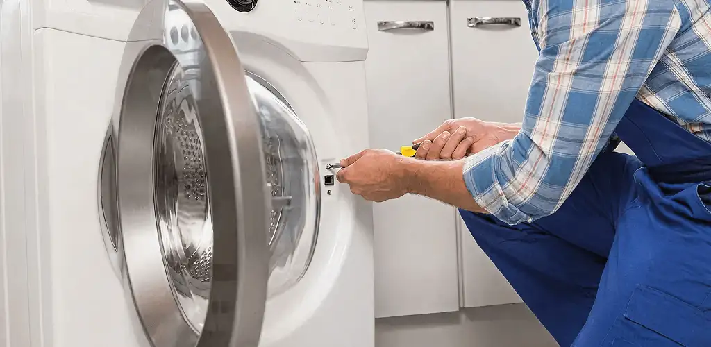 Handyman repairing a clothes dryer and checking electrical connections in Kansas City, KS