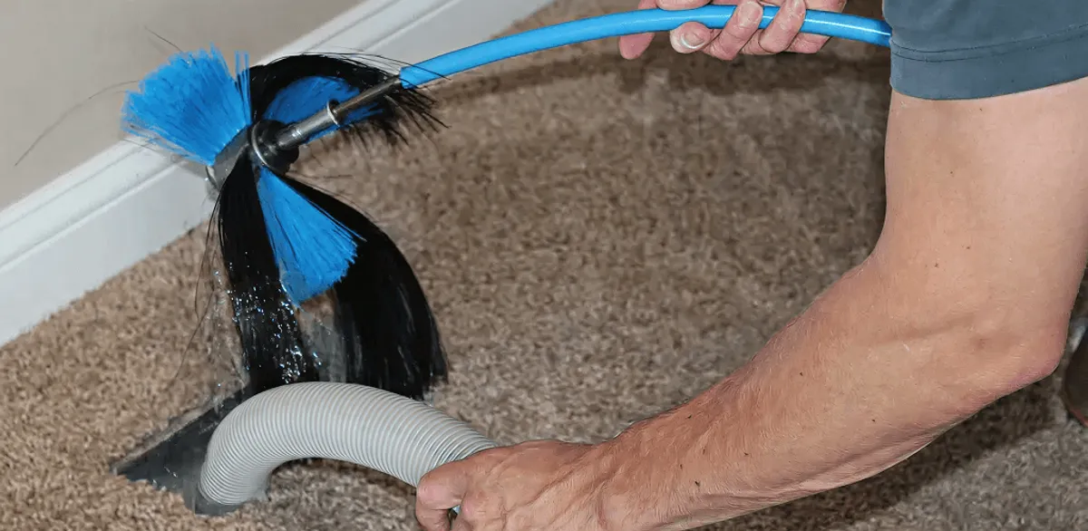 Dryer vent cleaning technician brushing lint from a vent line in Kansas City, KS