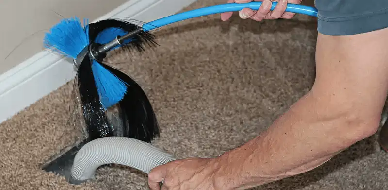 Dryer vent cleaning technician brushing lint from a vent line in Kansas City, KS