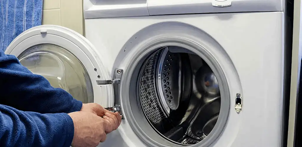 Washing machine repair handyman checking a front-load washer door and latch in Kansas City, KS