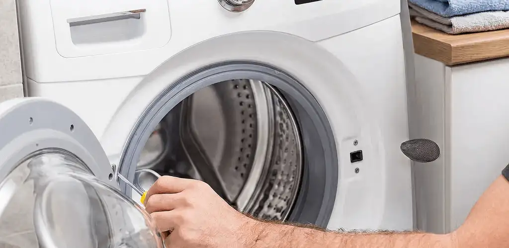 Handyman repairing a front-load washing machine and inspecting the drum in Kansas City, KS