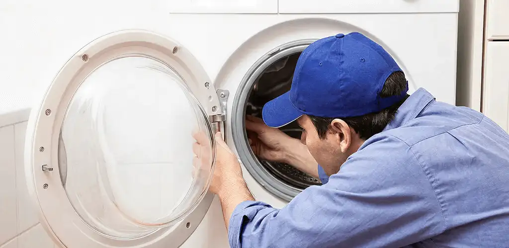 Washing machine repair handyman inspecting a front-load washer drum in Kansas City, KS
